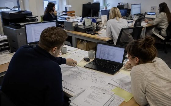 Dwie osoby w biurze pracują nad dokumentami rozłożonymi na biurku